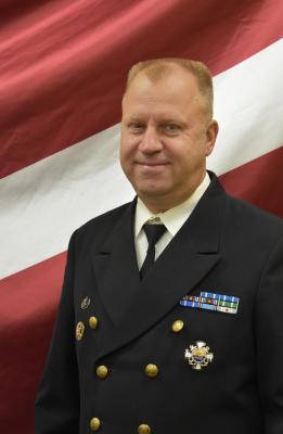 Andris Skribis uz Latvijas karoga fona svētku formas tērpā