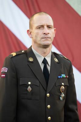 TRNC virsseržants virsseržants Artūrs Cvirko ikdienas formastērpā uz Latvijas karoga fona