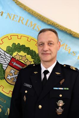 2.RNC virsseržants štāba virsseržants Atis Dadzītis svētku formas tērpā uz 2.RNC karoga fona
